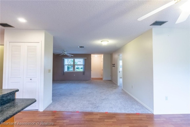 interior space with a textured ceiling, hardwood / wood-style flooring, and ceiling fan