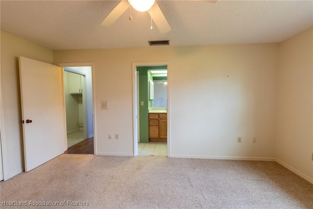 unfurnished bedroom with light carpet, ensuite bath, ceiling fan, a spacious closet, and a closet