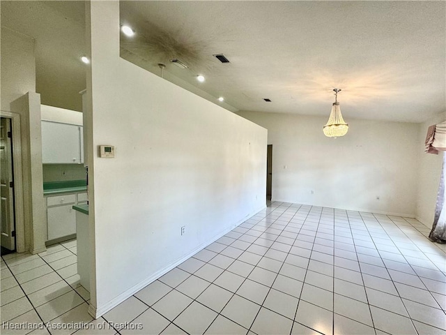 unfurnished room featuring lofted ceiling, light tile patterned flooring, and visible vents