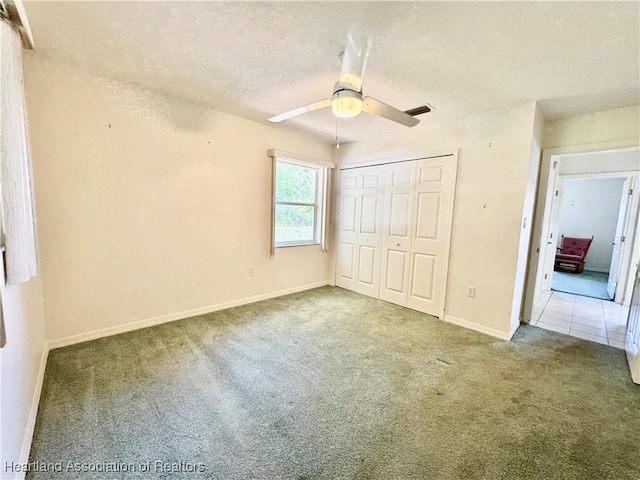 unfurnished bedroom featuring a textured ceiling, carpet floors, visible vents, baseboards, and a closet