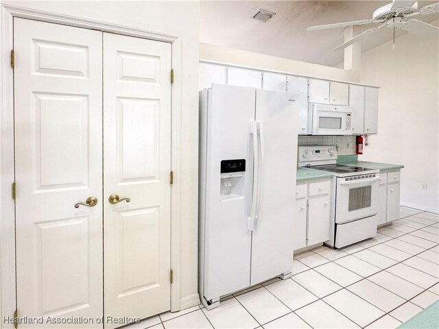 kitchen with white appliances, visible vents, white cabinets, vaulted ceiling, and tasteful backsplash