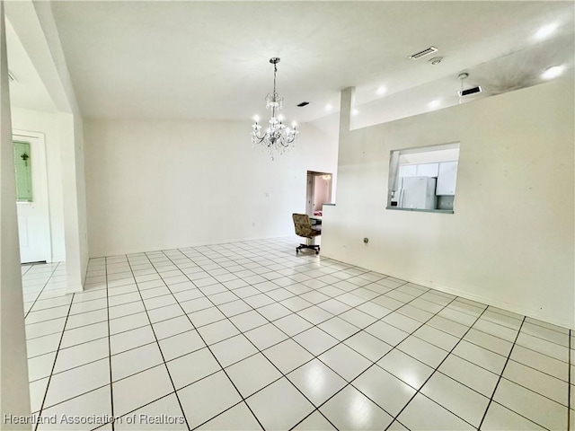 spare room featuring lofted ceiling, light tile patterned flooring, and an inviting chandelier