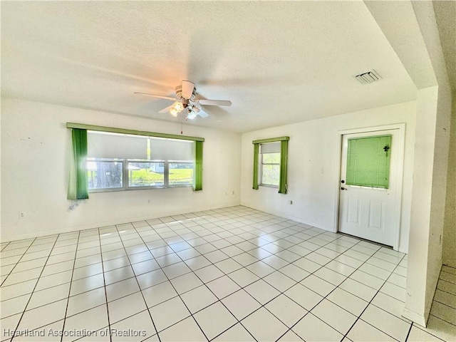 unfurnished room with a ceiling fan, visible vents, a textured ceiling, and light tile patterned floors