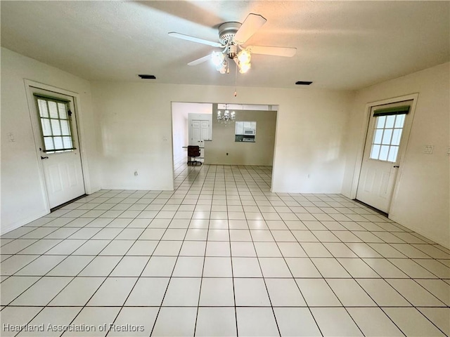 empty room featuring a ceiling fan, visible vents, and light tile patterned floors