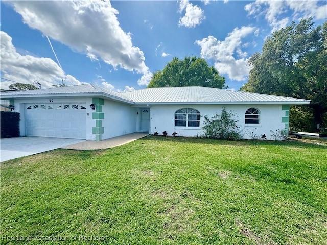 ranch-style house with metal roof, a garage, concrete driveway, stucco siding, and a front yard