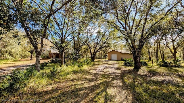 view of yard with an outbuilding, dirt driveway, and a garage