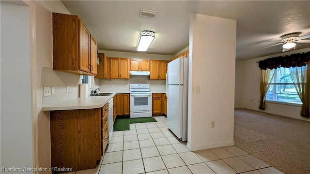 kitchen with light carpet, white appliances, light countertops, under cabinet range hood, and light tile patterned flooring