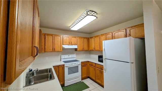 kitchen featuring white appliances, under cabinet range hood, light countertops, and a sink