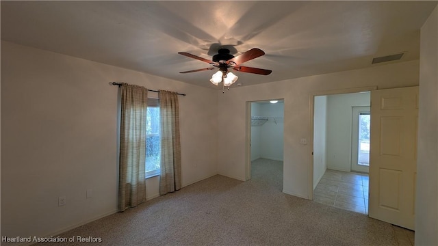 unfurnished room featuring light carpet, ceiling fan, visible vents, and light tile patterned flooring