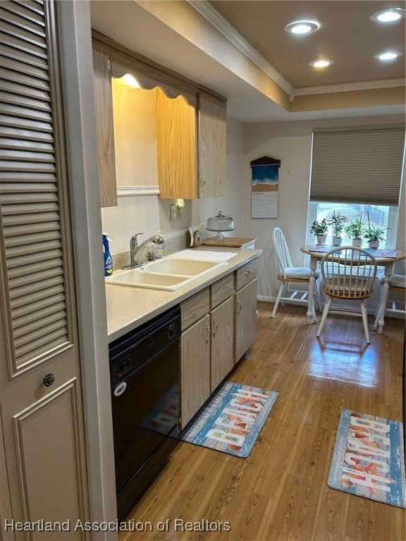 kitchen featuring a sink, light countertops, ornamental molding, light wood-type flooring, and dishwasher