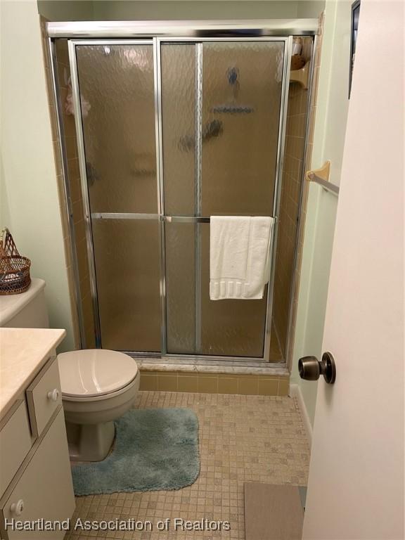 full bath featuring vanity, a shower stall, toilet, and tile patterned floors