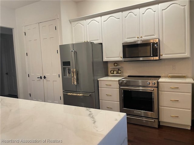 kitchen featuring white cabinets, dark hardwood / wood-style flooring, backsplash, stainless steel appliances, and light stone countertops