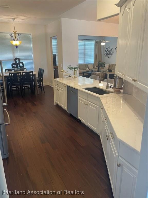131 Temptation Ct, Lake Placid, FL 33852 - kitchen featuring stainless steel dishwasher, a sink, dark wood finished floors, white cabinets, and decorative light fixtures