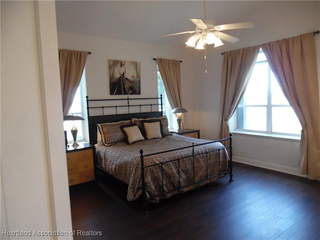 bedroom with wood finished floors, baseboards, a ceiling fan, and multiple windows