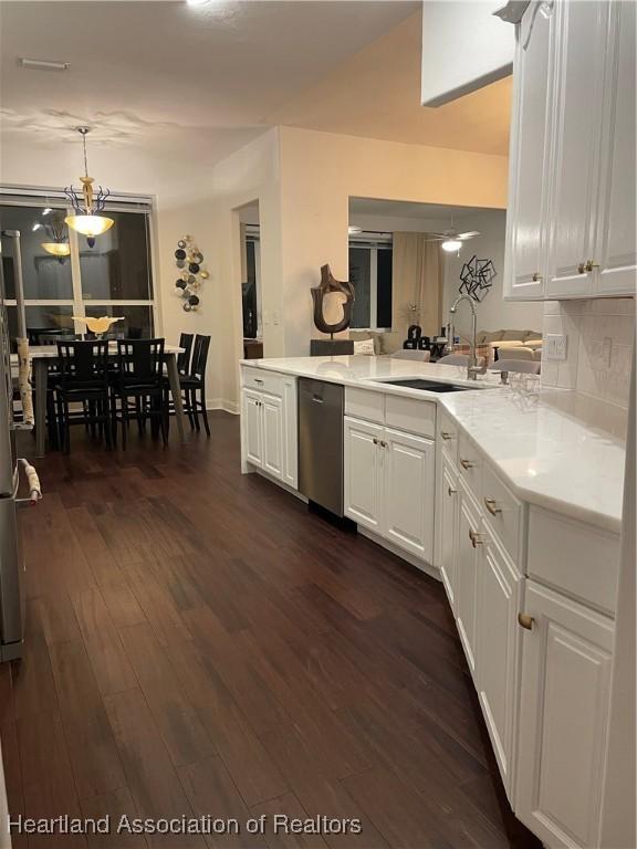 kitchen with sink, white cabinetry, decorative light fixtures, stainless steel dishwasher, and dark hardwood / wood-style flooring