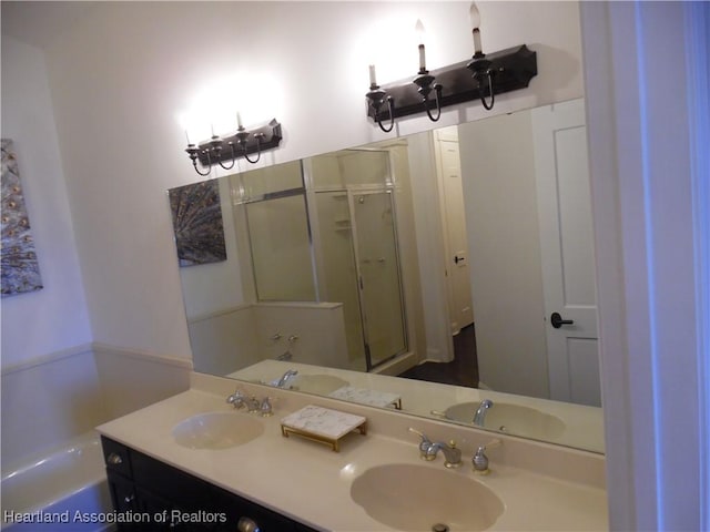 bathroom with a stall shower, double vanity, and a sink