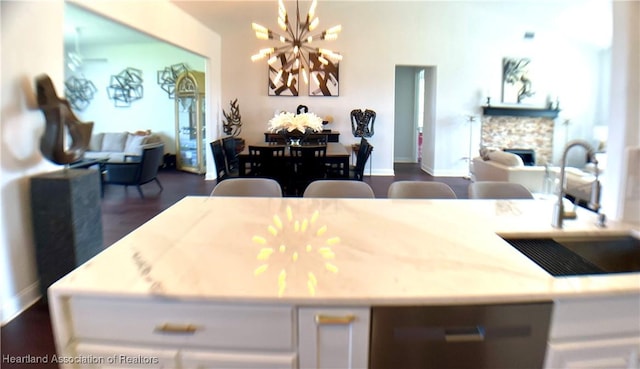 kitchen with a sink, dark wood finished floors, open floor plan, a chandelier, and dishwasher
