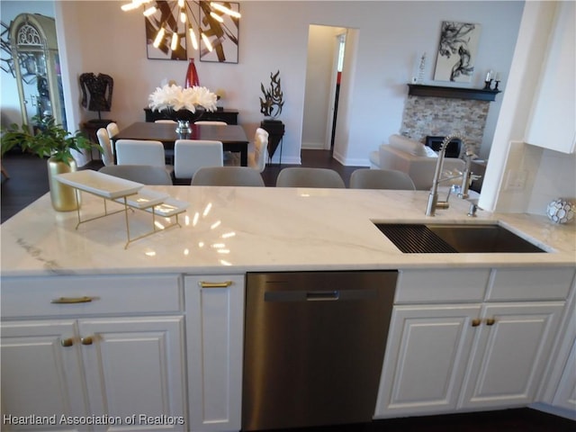 kitchen featuring light stone counters, white cabinets, a sink, a chandelier, and dishwasher