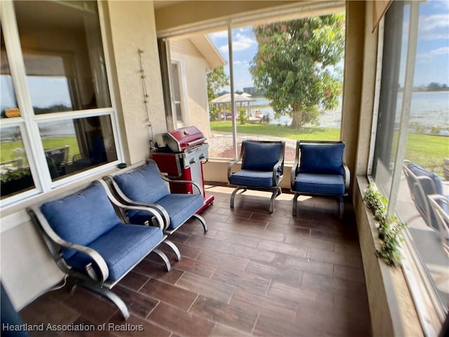 sunroom featuring a water view