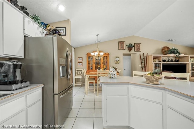 kitchen featuring kitchen peninsula, vaulted ceiling, light tile patterned floors, decorative light fixtures, and white cabinets