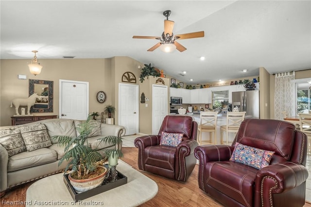 living room featuring light wood-type flooring, vaulted ceiling, and ceiling fan