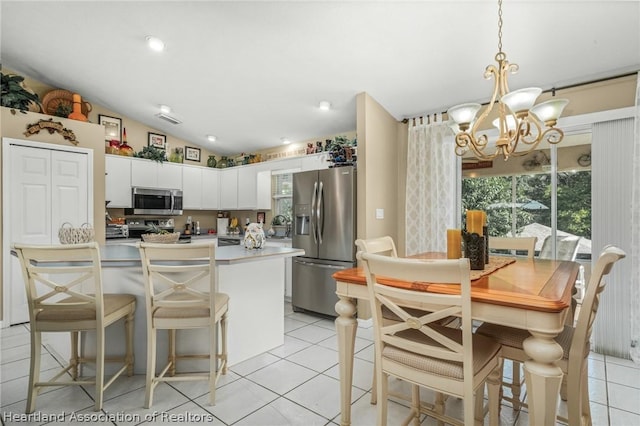 kitchen featuring white cabinetry, pendant lighting, vaulted ceiling, light tile patterned floors, and appliances with stainless steel finishes