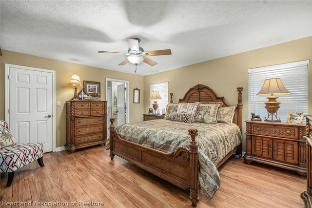 bedroom featuring ceiling fan, light hardwood / wood-style flooring, a textured ceiling, and ensuite bath