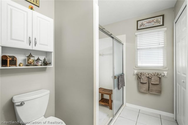 bathroom with tile patterned floors, toilet, and a shower with door