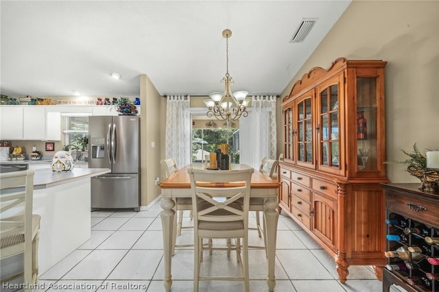 dining space with a chandelier, light tile patterned floors, and vaulted ceiling