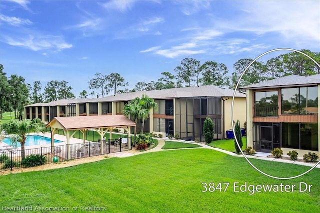 rear view of property with a fenced in pool and a lawn