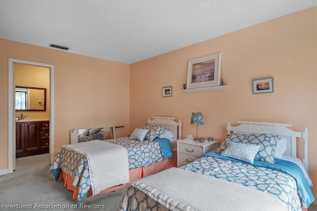 carpeted bedroom with a textured ceiling and ensuite bath