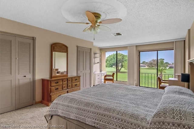 bedroom with access to exterior, a textured ceiling, light colored carpet, ceiling fan, and multiple closets