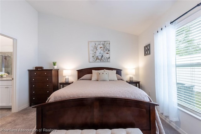 bedroom featuring connected bathroom, vaulted ceiling, and light carpet