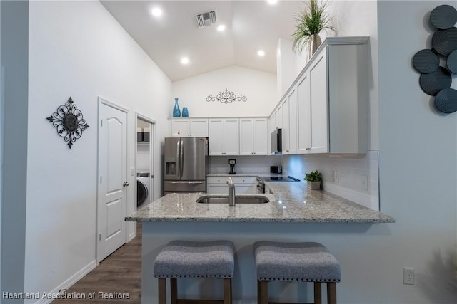 kitchen featuring sink, white cabinetry, light stone counters, kitchen peninsula, and appliances with stainless steel finishes