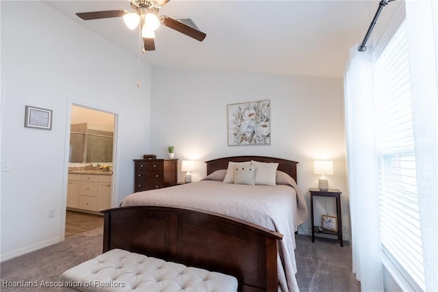 bedroom featuring ceiling fan, ensuite bathroom, vaulted ceiling, and light carpet