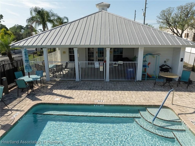 rear view of house featuring a community pool and a patio