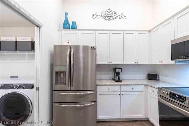 kitchen featuring stainless steel appliances, washer / clothes dryer, light stone counters, and white cabinets