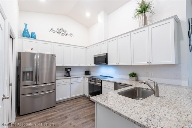 kitchen featuring light stone counters, kitchen peninsula, stainless steel appliances, white cabinets, and sink