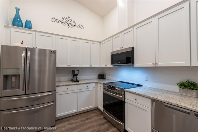 kitchen with white cabinets, stainless steel appliances, dark hardwood / wood-style floors, and light stone countertops