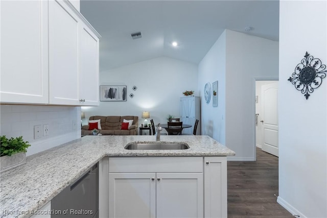 kitchen featuring light stone counters, kitchen peninsula, lofted ceiling, white cabinetry, and sink