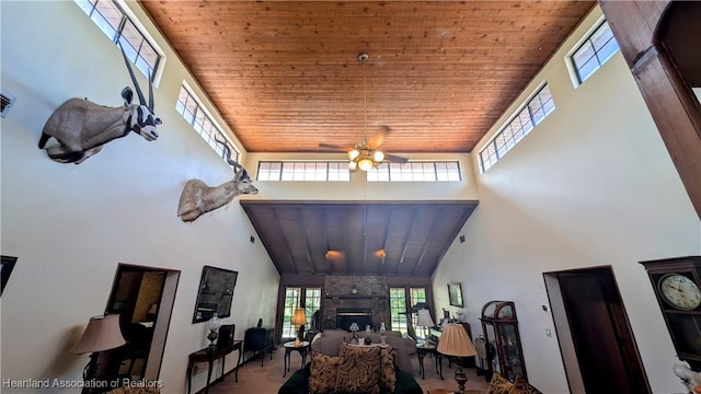 living room with wood ceiling, ceiling fan, a fireplace, and a high ceiling