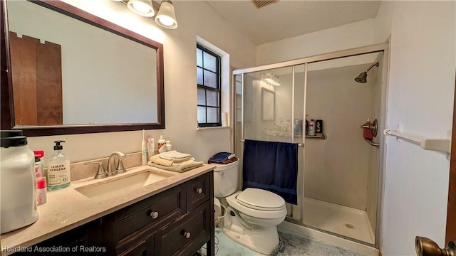 bathroom with vanity, toilet, and a shower with door