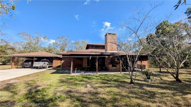 rear view of property featuring a carport and a yard