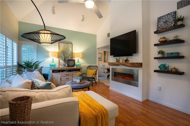 751 Grenada St, Port St Lucie, FL 34983 - living room with wood finished floors, high vaulted ceiling, ceiling fan, a glass covered fireplace, and baseboards