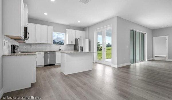 kitchen with appliances with stainless steel finishes, a center island, decorative backsplash, and white cabinets