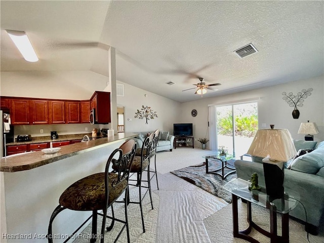 living area with a ceiling fan, a textured ceiling, visible vents, light carpet, and lofted ceiling