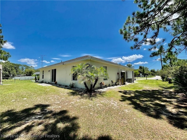view of side of property featuring a yard, stucco siding, and fence