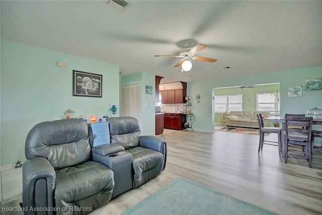 living room with light hardwood / wood-style flooring and ceiling fan