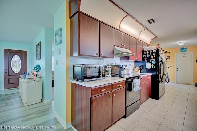 kitchen with backsplash, light tile patterned flooring, and black appliances