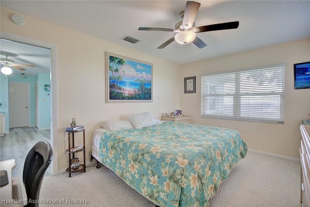 carpeted bedroom featuring ceiling fan and a textured ceiling